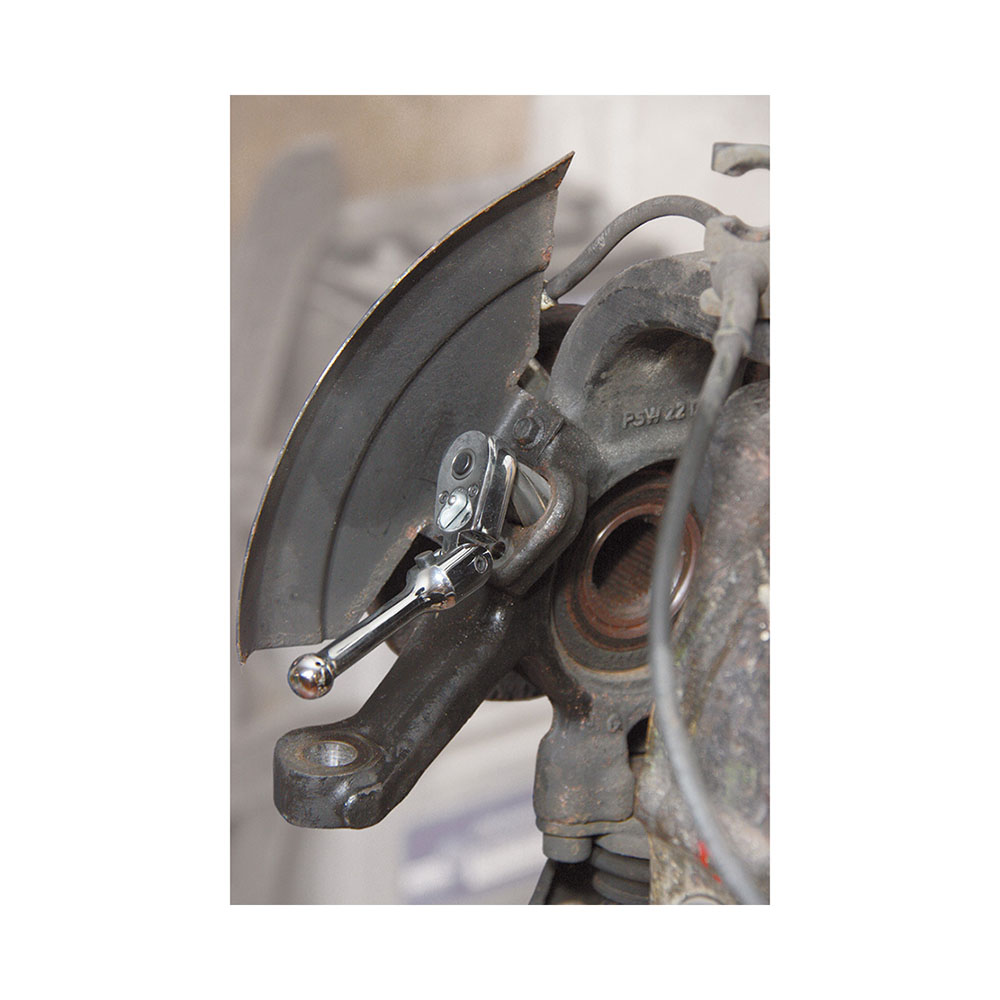 Werkzeuge – Qualität für Profis Nahaufnahme einer Autobremsenbaugruppe mit Bremssattel und -scheibe. Ein verstellbarer Schraubenschlüssel aus Ihrem Condor Reibahlen-Satz für Aufnahmebohrung von ABS-Sensoren, 8-tlg., ist an einer Schraube der Baugruppe befestigt und demonstriert die Präzision und Zuverlässigkeit, die für das Werkzeugset eines jeden Hobbymechanikers unverzichtbar sind. Jetzt kaufen