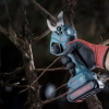 Werkzeuge – Qualität für Profis Eine Hand in einem Handschuh hält eine kabellose elektrische Astschere „RONIX Bürstenlose Akku-Astschere 28 mm“, um einen Ast abzuschneiden; im Hintergrund sind Bäume und Äste zu sehen. Jetzt kaufen