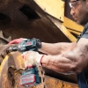 Werkzeuge – Qualität für Profis Eine Person zieht mit einem kabellosen Ronix 20V-Schlagschrauber eine große Schraube an einer Industriemaschine fest, wobei sie eine Schutzbrille und Handschuhe trägt. Jetzt kaufen